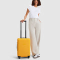 woman standing with yellow carry on suitcase